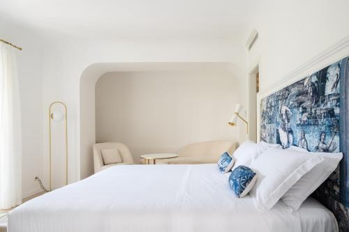 a white bedroom with a large white bed with blue pillows at La Residenza Capri in Capri