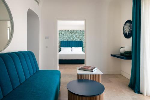a living room with a blue couch and a bed at La Residenza Capri in Capri
