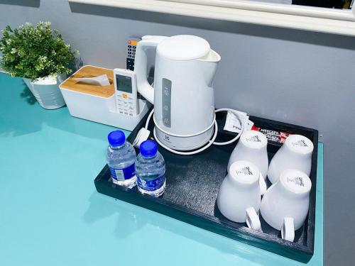 a shelf with a coffee maker and bottles of water at 61 Hotel in Gua Musang