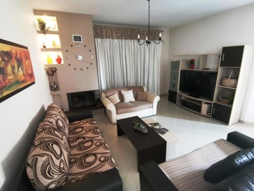 ein Wohnzimmer mit einem Sofa und einem TV in der Unterkunft KEY POINT Town House in Korfu-Stadt
