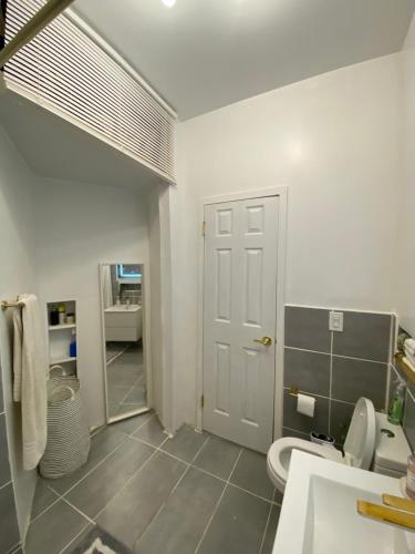 a bathroom with a toilet and a sink and a door at Luxury Apt - 3 Stops to "Time Square" in New York