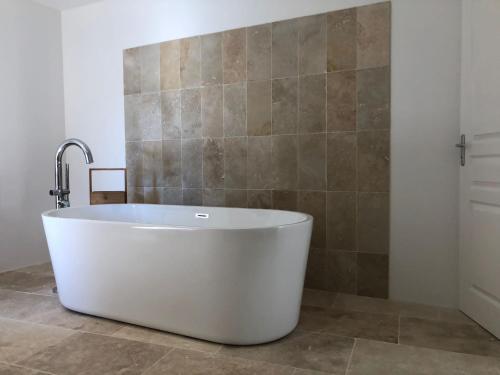 y baño con bañera y pared de azulejos. en Maison Delière, en Venterol