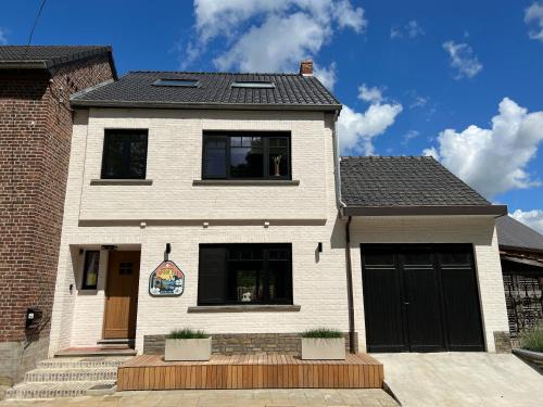 a white house with black garage doors on it at Vakantiewoning Spoor 23 in Borgloon