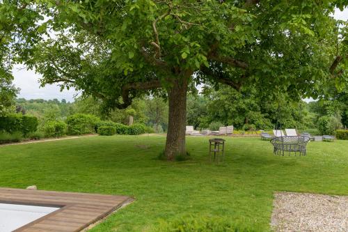 a tree in a yard with a table and chairs at Rue Haute by M&M 4 sterren bed en breakfast vlakbij Maastricht in Eben-Emael