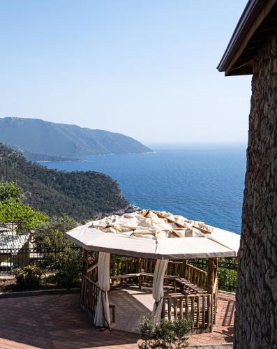 a table with a white umbrella and the ocean at Casa Di Pietra in Fethiye