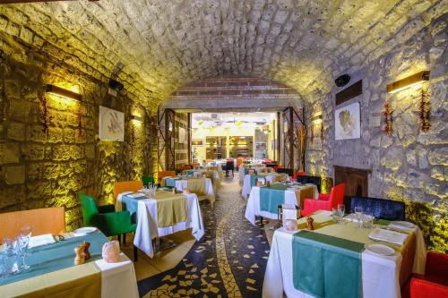 un restaurante con mesas blancas y sillas coloridas en Hotel Savoia Sorrento, en Sorrento