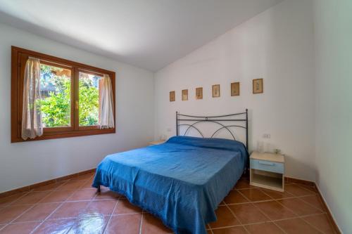 une chambre avec un lit bleu et une fenêtre dans l'établissement House in San Teodoro among the scents of Sardinia, à San Teodoro