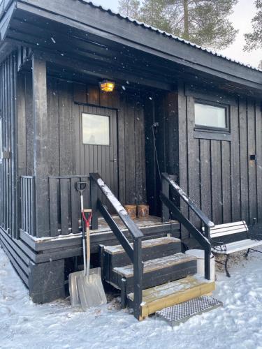 a cabin with snow on the stairs and a snow shovel at 1125 Fjällstugan in Lofsdalen
