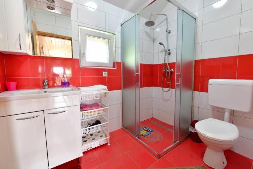 a red and white bathroom with a toilet and a shower at Apartments Laura in Rakovica