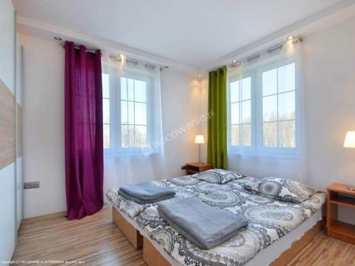a bedroom with a large bed with purple and green curtains at pokoje goscinne Damian in Mrzeżyno