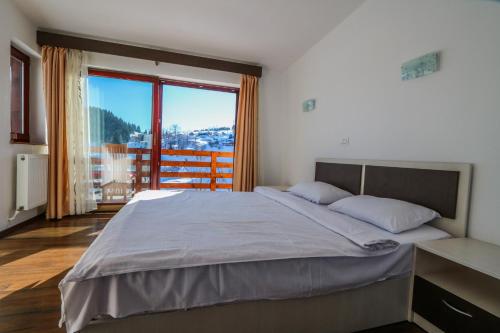 a bedroom with a large bed and a large window at Pensiunea Daria in Fundata
