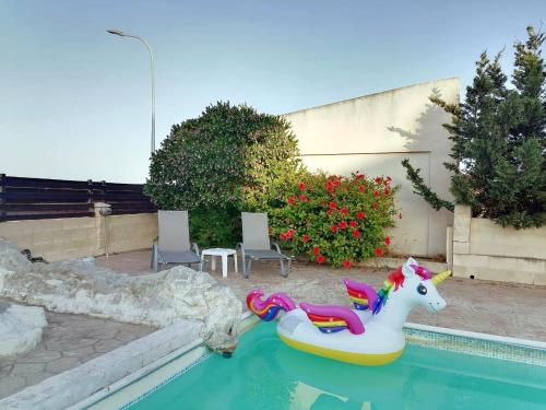 a pool with a unicorn inflatable toy in the water at Afroditi Apartment in Perivolia