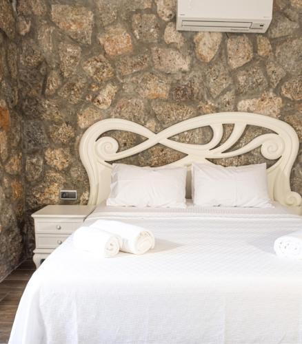 a bedroom with a white bed with a stone wall at Casa Di Pietra in Fethiye