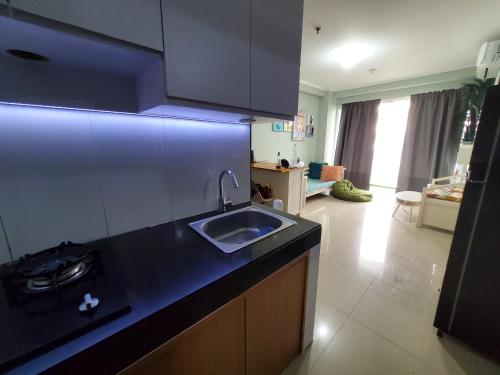 a kitchen with a sink and a living room at Apartment Gateway pasteur in Bandung