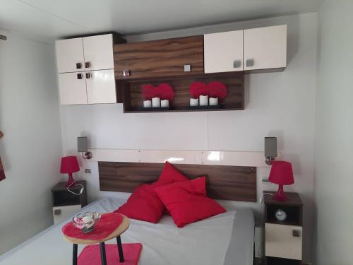 Un dormitorio con una cama con almohadas rojas y una mesa. en Chalet Dolus-d'Oléron, 3 pièces, 4 personnes - FR-1-246A-120, en Dolus d'Oléron