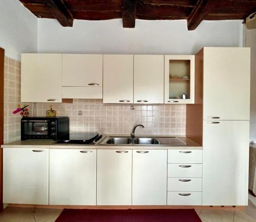 a kitchen with white cabinets and a sink at Pizzo Casale in Vico del Gargano