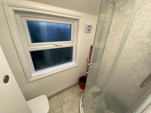 La salle de bains est pourvue d'une douche en verre et d'une fenêtre. dans l'établissement Small Single room walking distance to Hove Station, à Brighton et Hove