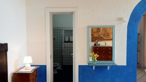 Habitación con una pared azul y blanca y un espejo. en AGRITURISMO CASA GIALLA en Lipari