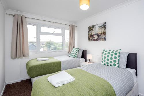 1 dormitorio con 2 camas y ventana en Tms Lovely 3 Bed House-Tilbury-Free parking, en Tilbury