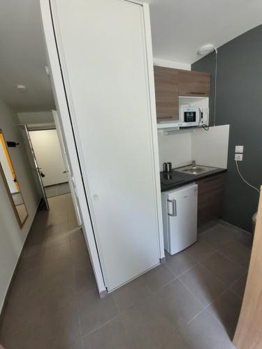 Cette chambre comprend une petite cuisine avec un réfrigérateur blanc. dans l'établissement Résidence Néméa mondial 98, à Montpellier