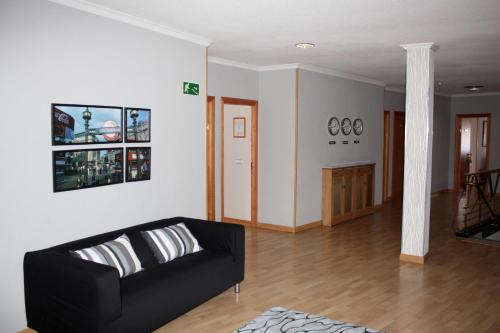 ein Wohnzimmer mit einem schwarzen Sofa und Holzböden in der Unterkunft AP Hotel Madrid Airport in Madrid
