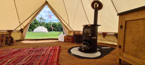 a stove in a tent with a field in the background at Park Farm Holidays Glamping in Lyndhurst