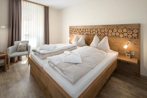 una camera da letto con un grande letto bianco con testiera in legno di Hotel Zur Post a Bad Abbach