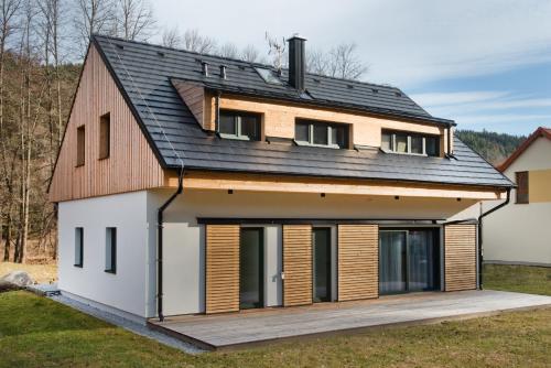 a house with a gambrel roof and a deck at Hygge Apartments in Rožmberk nad Vltavou