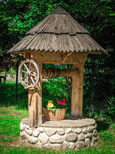 a wooden gazebo with a wheel and a basket of flowers at Tatra House Residence in Zakopane