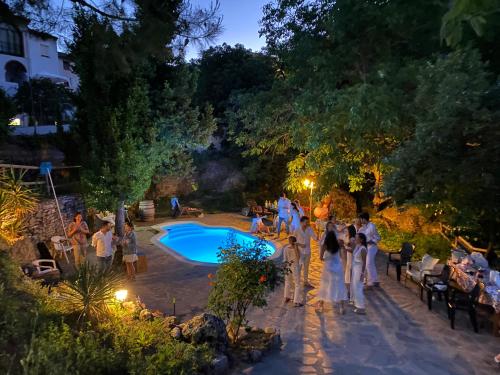un grupo de personas de pie alrededor de una piscina por la noche en Casa La Muralla, en Ronda