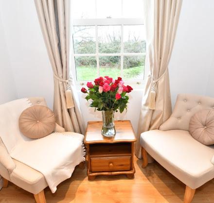 a living room with two chairs and a vase of flowers on a table at The Rocks B&B in Crumlin