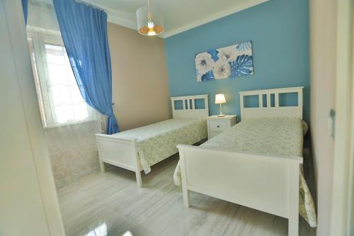Un dormitorio con dos camas con paredes azules y una ventana. en Villa Ivanda Beach - Xenia Sicily Villas, en Mazara del Vallo
