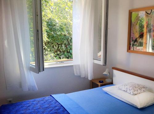 a bedroom with a blue bed and a window at Apartment Adriana in Supetar