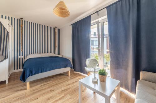 een slaapkamer met blauwe gordijnen en een bed en een bank bij Apartamenty Białe Piaski in Jastarnia