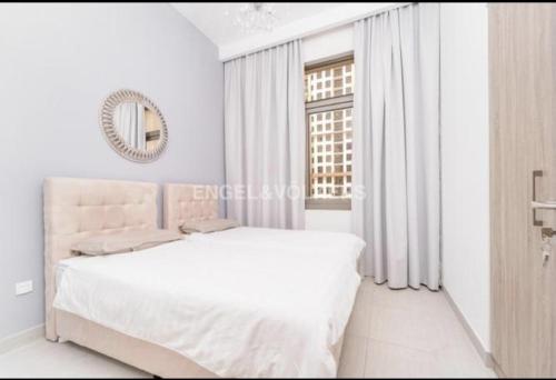 a white bedroom with a bed and a mirror at TOWN SQUAR PARK VIEW in Dubai