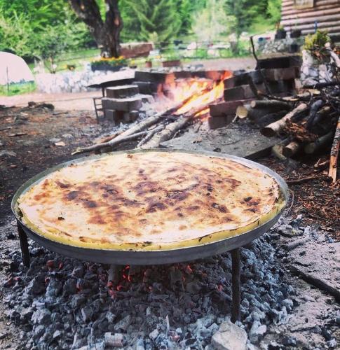 a pizza cooking on a grill with a fire at Guest house Hyrmet Demushi in Valbonë