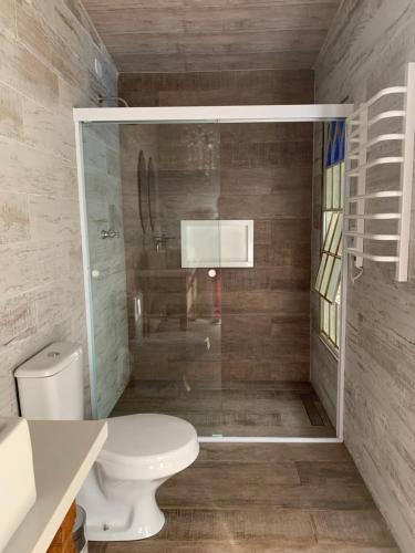 a bathroom with a toilet and a glass shower at Hospedagem Casadalee chalé com piscina privativa aquecida e Apartamento sem piscina in Monte Verde