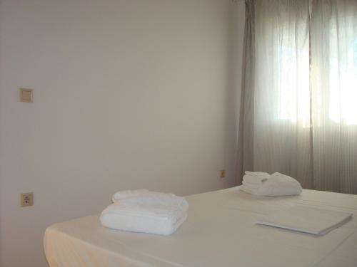a white room with towels on a bed at Merlot Village Rental Properties in Kariá