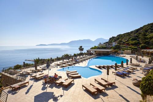 Blue Marine Resort and Spa Hotel في آغيوس نيكولاوس: منتجع فيه مسبح وكراسي والمحيط