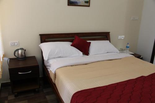1 cama con almohadas blancas y rojas en una habitación en Sri Lakshmi Estates, en Siddapur