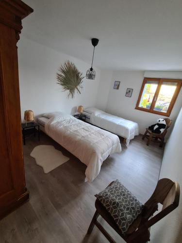 1 Schlafzimmer mit 2 Betten und einem Stuhl in der Unterkunft Agréable appartement avec Spa proche de la forêt in Bréchaumont