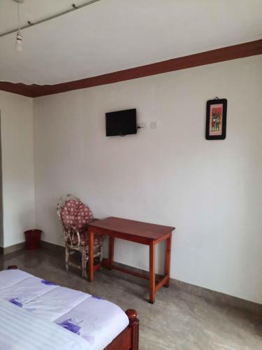 a bedroom with a desk and a tv on the wall at Airport Side Hotel Entebbe in Entebbe