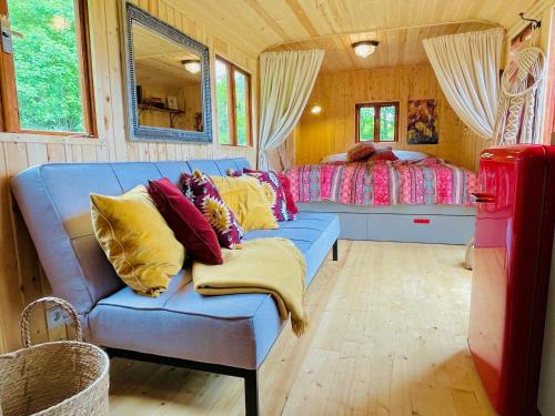 ein Wohnzimmer mit einem Sofa und einem Bett in der Unterkunft Maringotka Lipenka u Lipenské přehrady na Šumavě in Hořice na Šumavě