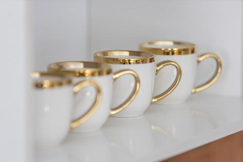 three gold and white coffee mugs sitting on a table at Historic Residence Apartments at Old Town in Tallinn