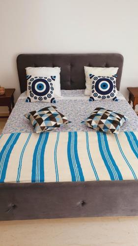 Appartement Corniche en bord de mer في سوسة: سرير به شراشف ووسائد زرقاء وبيضاء