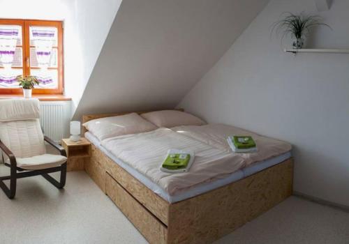 um pequeno quarto com uma cama e uma cadeira em Hotel Hospodářský dvůr Bohuslavice em Telč