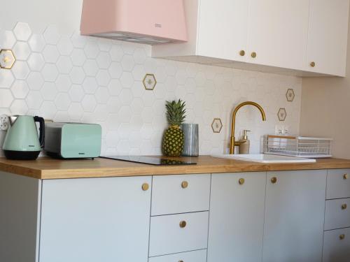a kitchen with white cabinets and a pineapple on the counter at Apartament Carmel Stegna Park in Stegna