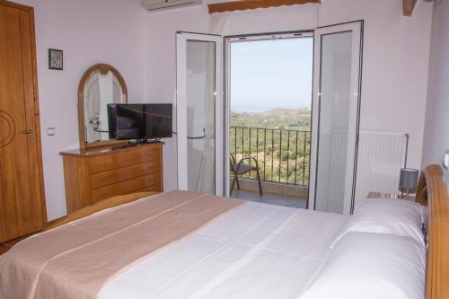 a bedroom with a bed and a television and a balcony at Villa Erofili Plakias south Rethimno Crete in Asómatoi