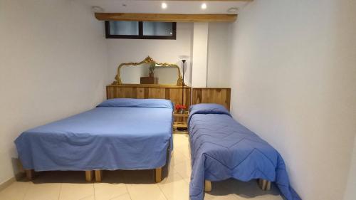 a room with two beds with blue sheets and a mirror at vallemaira house CASA BELVEDERE LUCE & SOLE 10 POSTI LETTO in San Damiano Macra