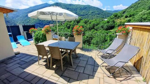 a patio with a table and chairs and an umbrella at vallemaira house CASA BELVEDERE LUCE & SOLE 10 POSTI LETTO in San Damiano Macra
